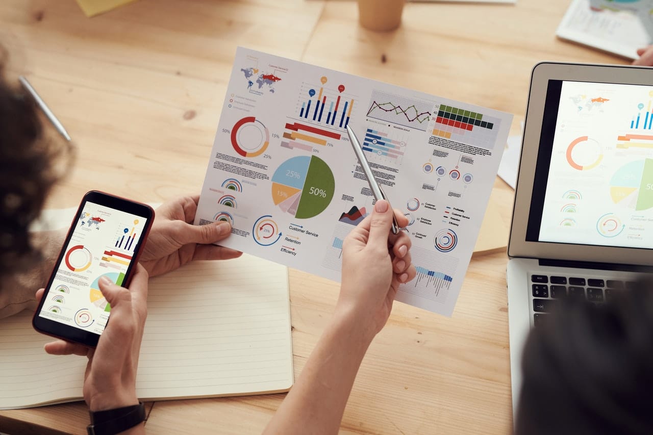 Hands holding a paper with graphs, charts, and data.