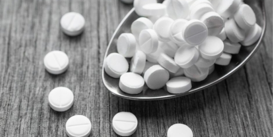 Pills falling out of a spoon.